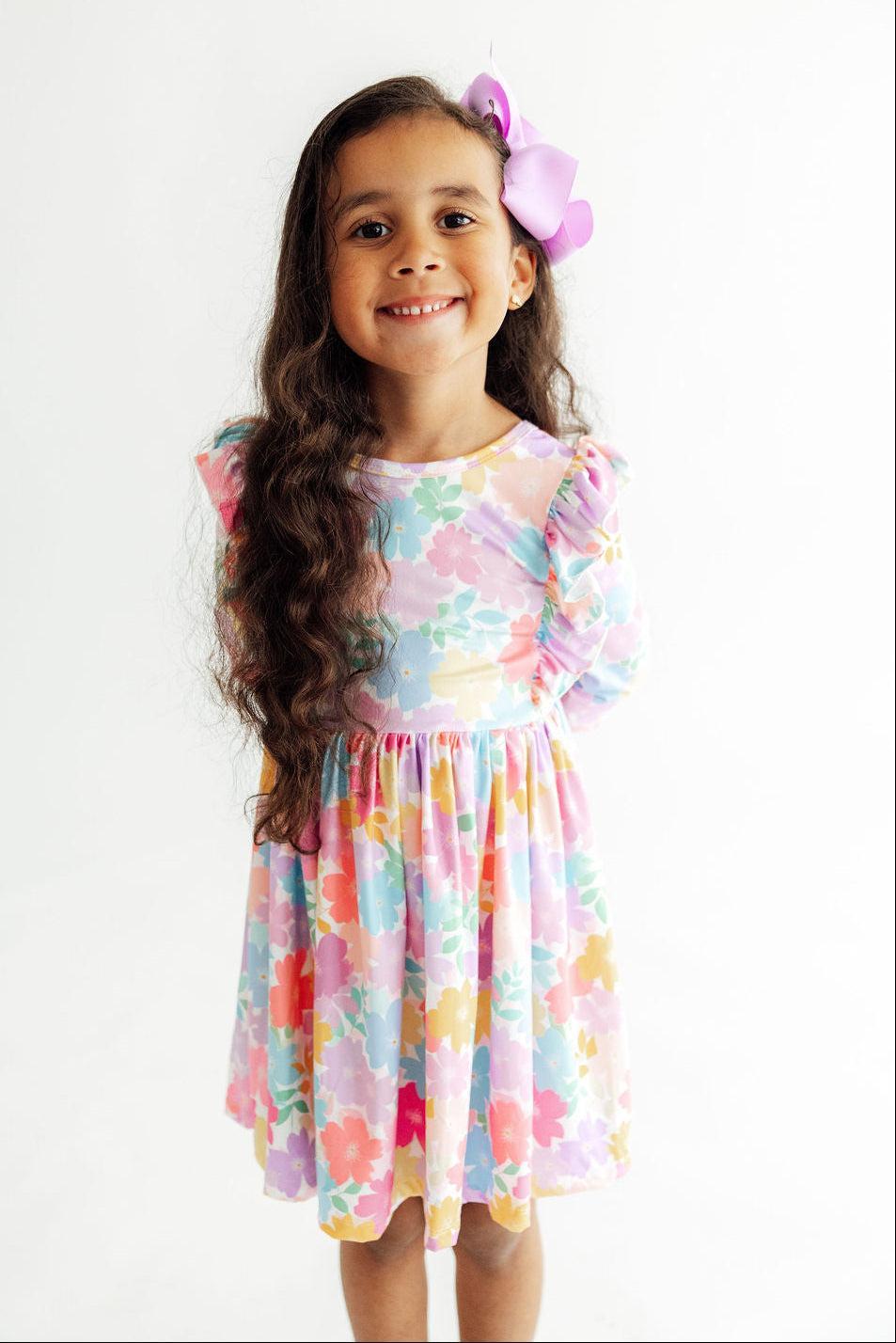 Young girl wearing a colorful floral dress with a white background