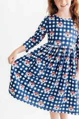 A young girl wearing a blue and white gingham dress with a repeating pattern of cartoon dog faces, shown against a plain white background.