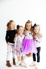 Four young girls posing together wearing colorful outfits on a white background