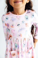 Child wearing a dress with Halloween-themed ghost and pumpkin print.