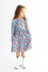 Young girl wearing a colorful floral dress with white boots on a white background