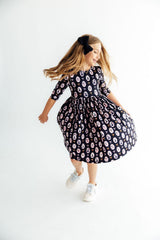 Young girl wearing a black floral dress on a white background