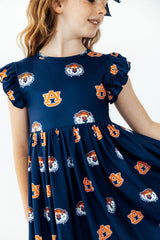 A young girl wearing a navy blue short-sleeve dress with an all-over Auburn Tigers logo and tiger head print, shown against a plain white background.