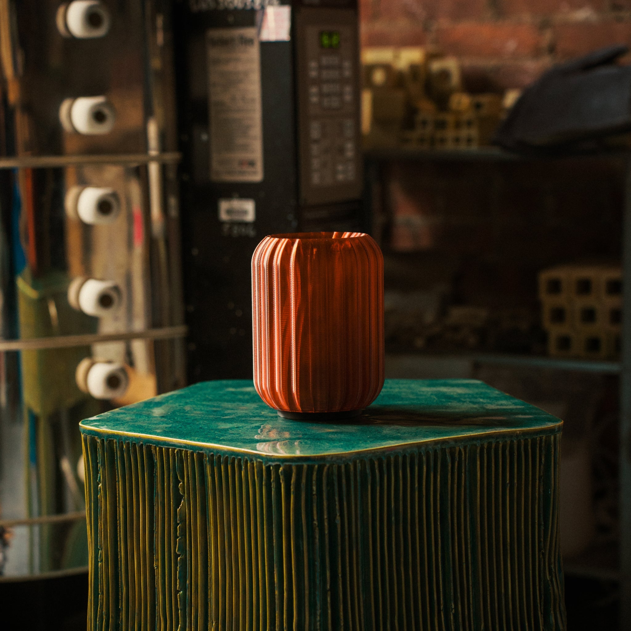Orange textured vase on a green surface with a blurred background