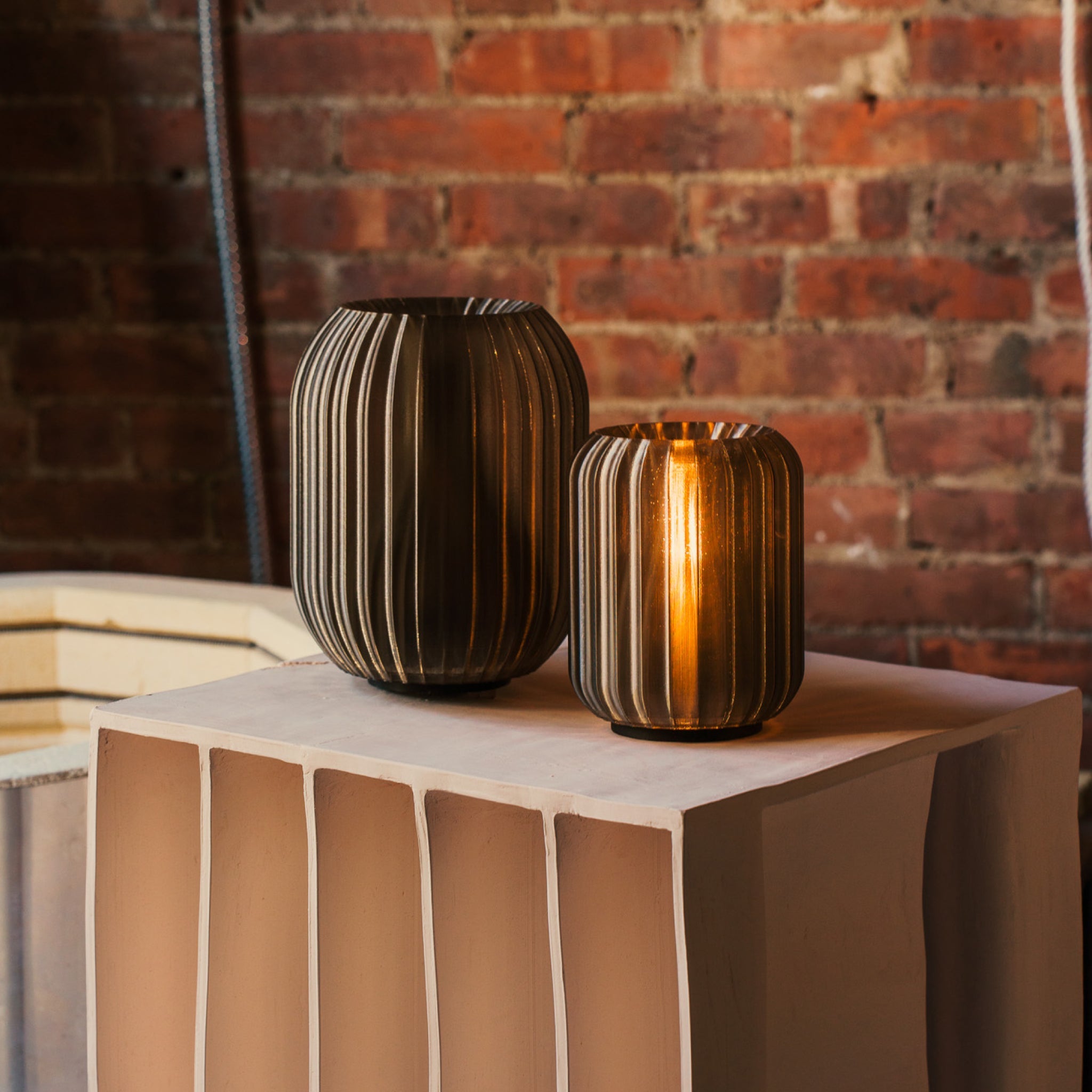 Two striped vases on a table with a brick wall background