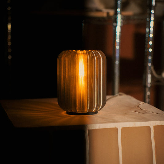 Decorative cylindrical lamp with ribbed design on a wooden surface