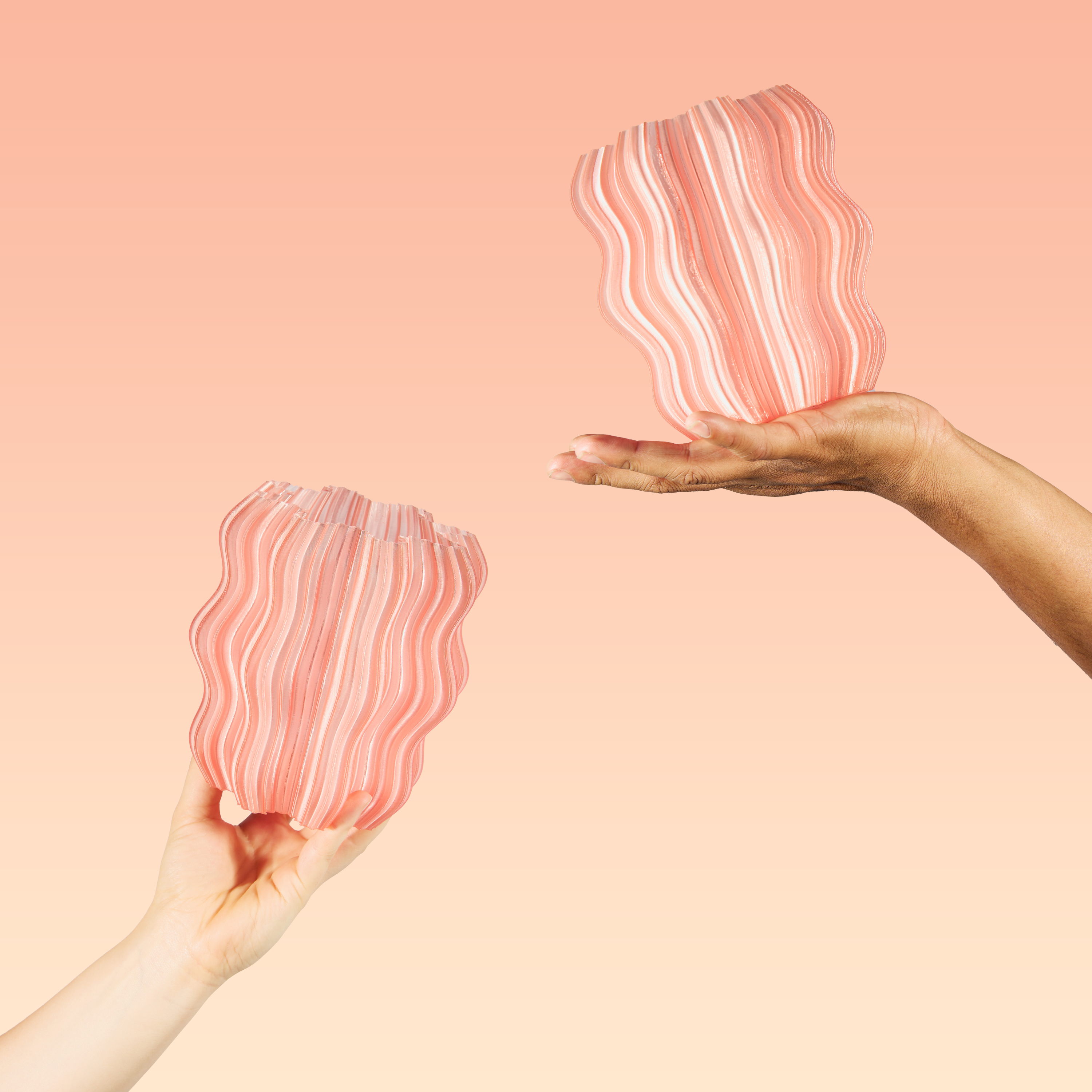 Two hands holding pink and white striped pouches against a peach background