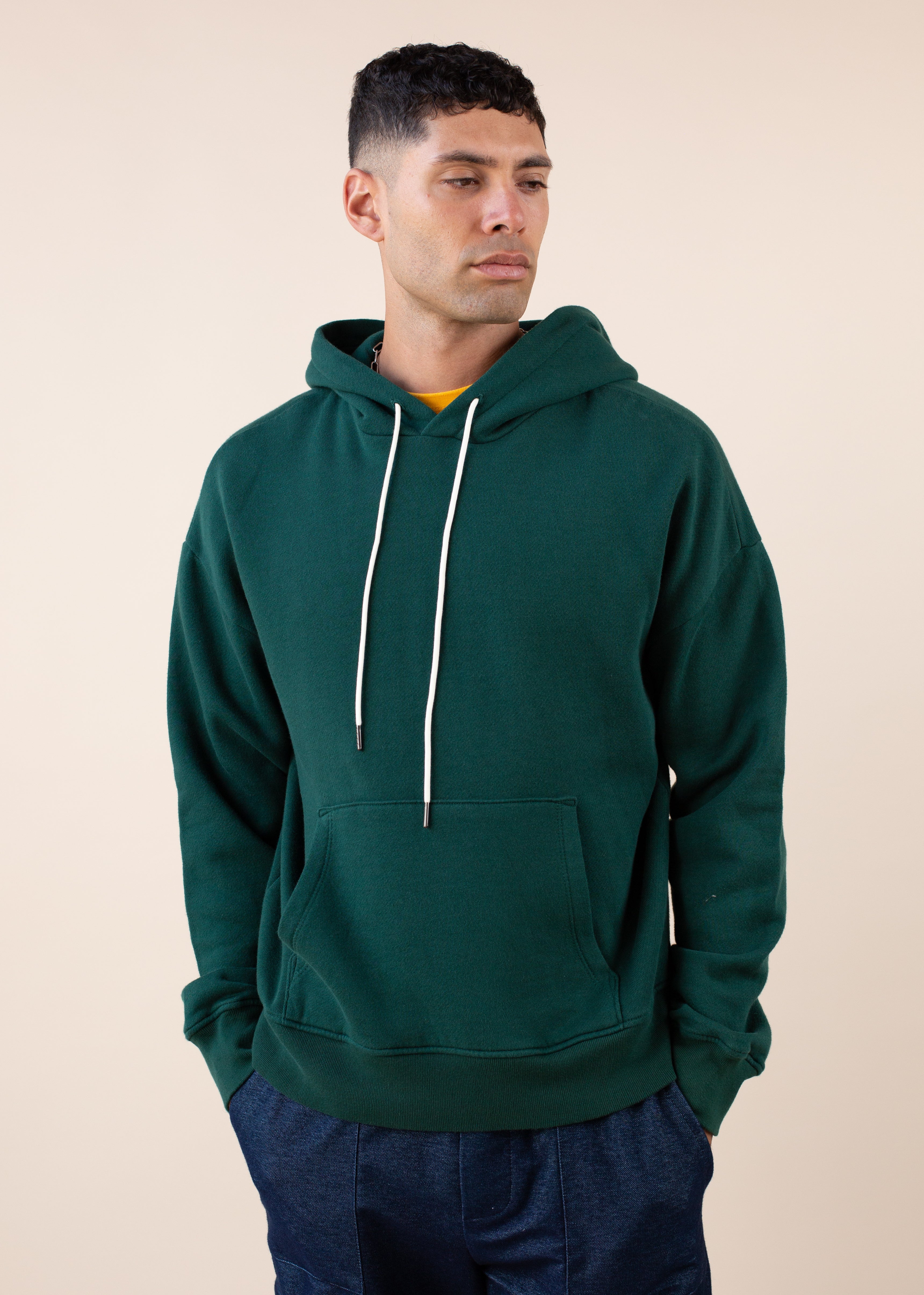 Man wearing a green hoodie against a beige background