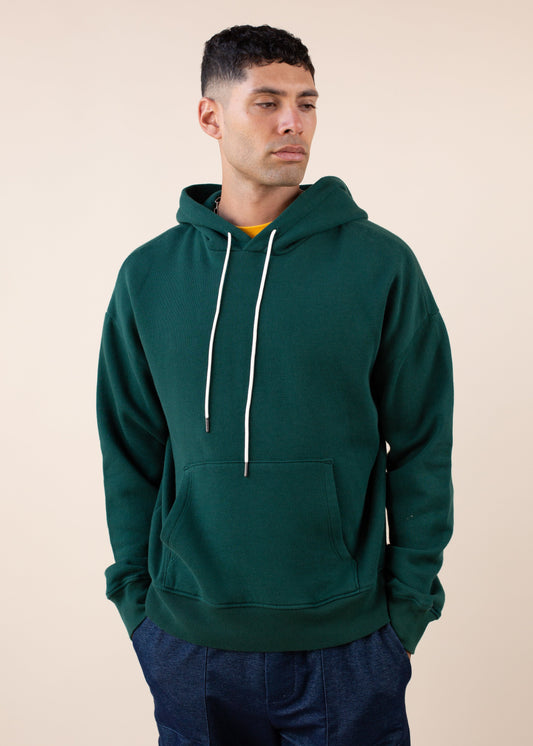 Man wearing a green hoodie against a beige background