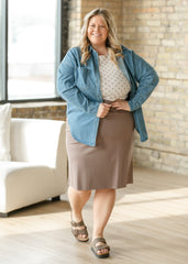 Woman wearing a denim jacket over a beige skirt in a well-lit room.
