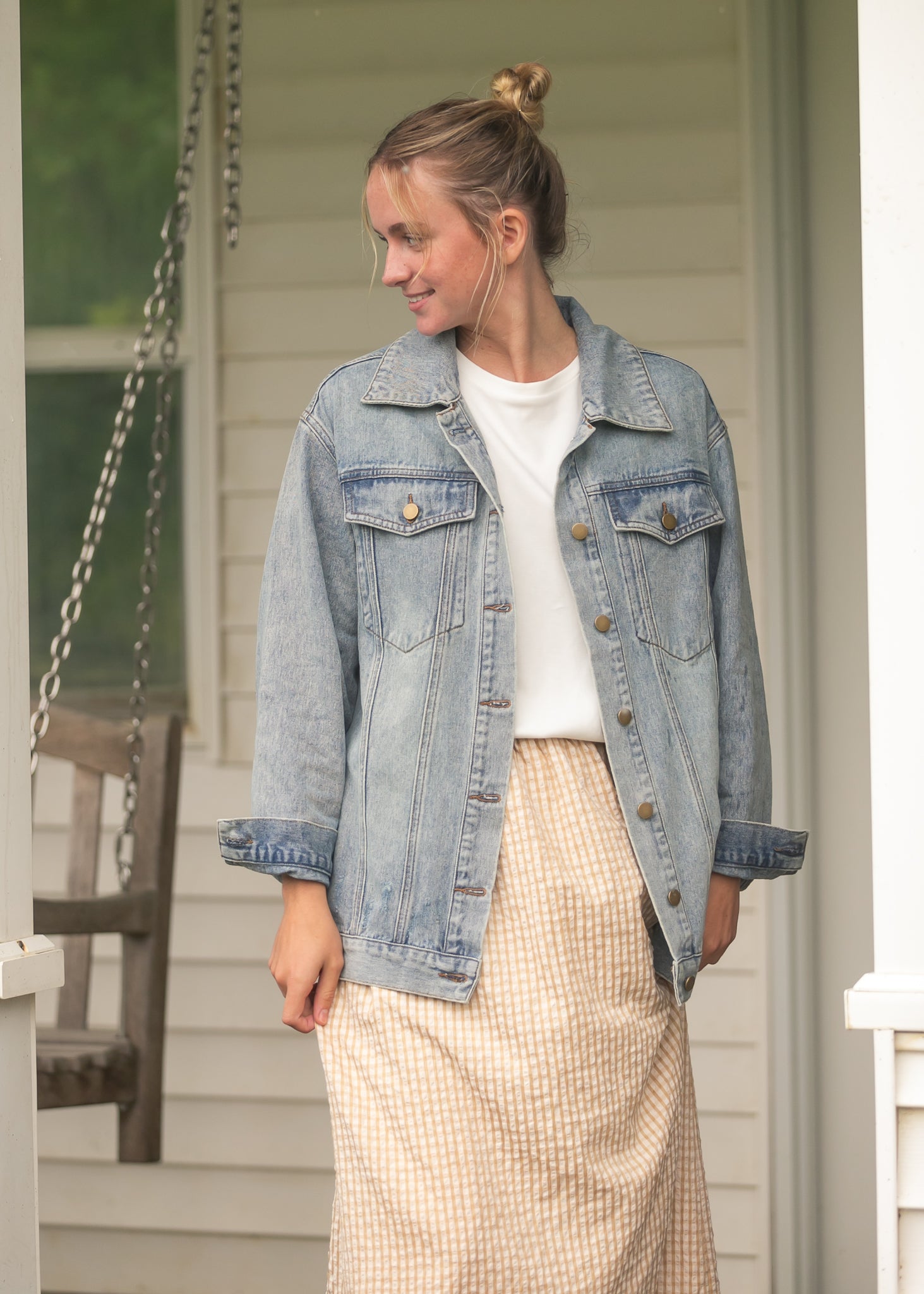 Woman wearing a denim jacket on a porch