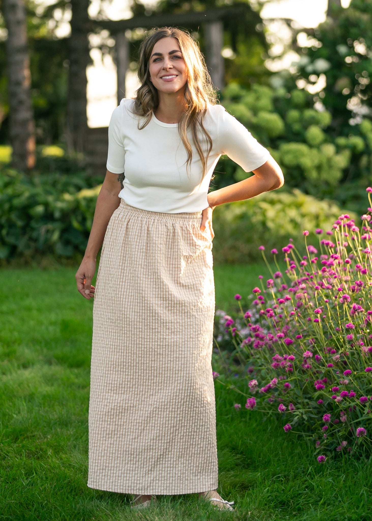 Woman standing outdoors in a garden with greenery and flowers