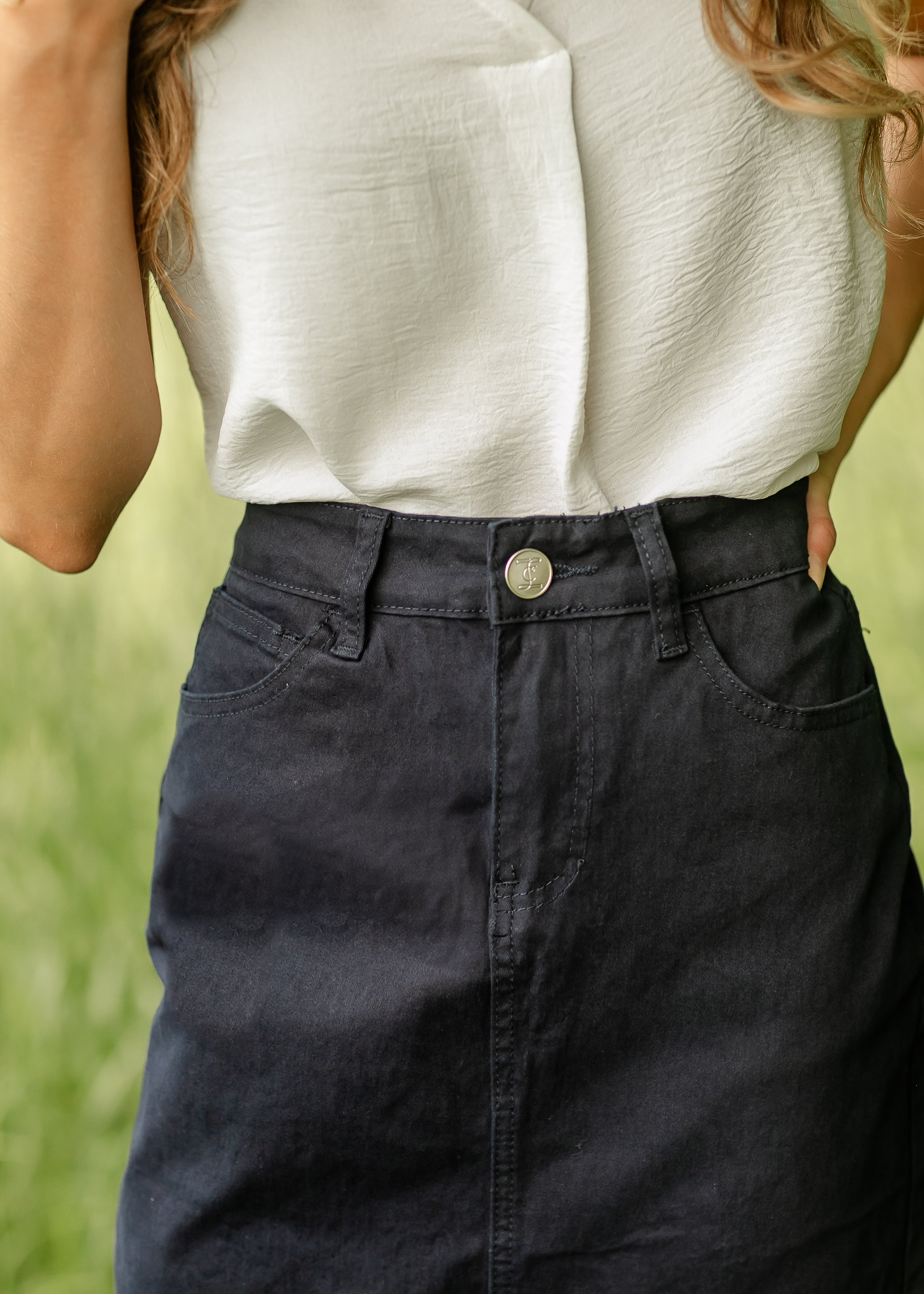 Person wearing a white top and dark pants with a blurred green background