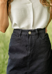 Person wearing a white top and dark pants with a blurred green background