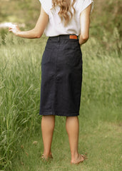 Person wearing a black skirt and white top standing in a grassy field
