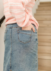 Person wearing a pink sweater and blue jeans with a blurred background