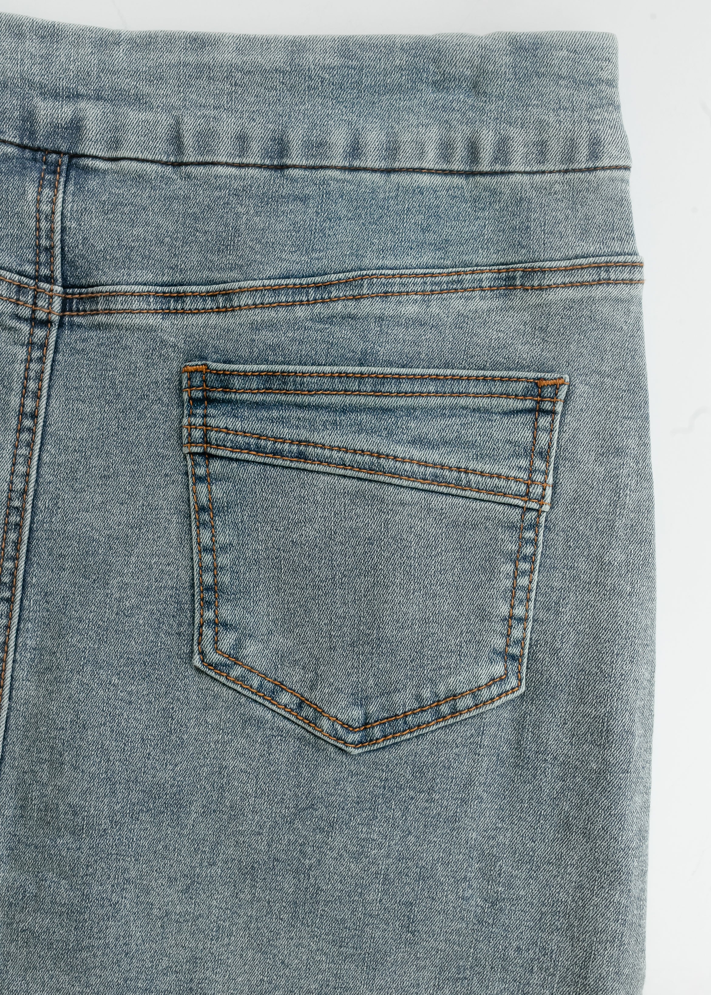 Close-up of a blue denim pocket on a white background
