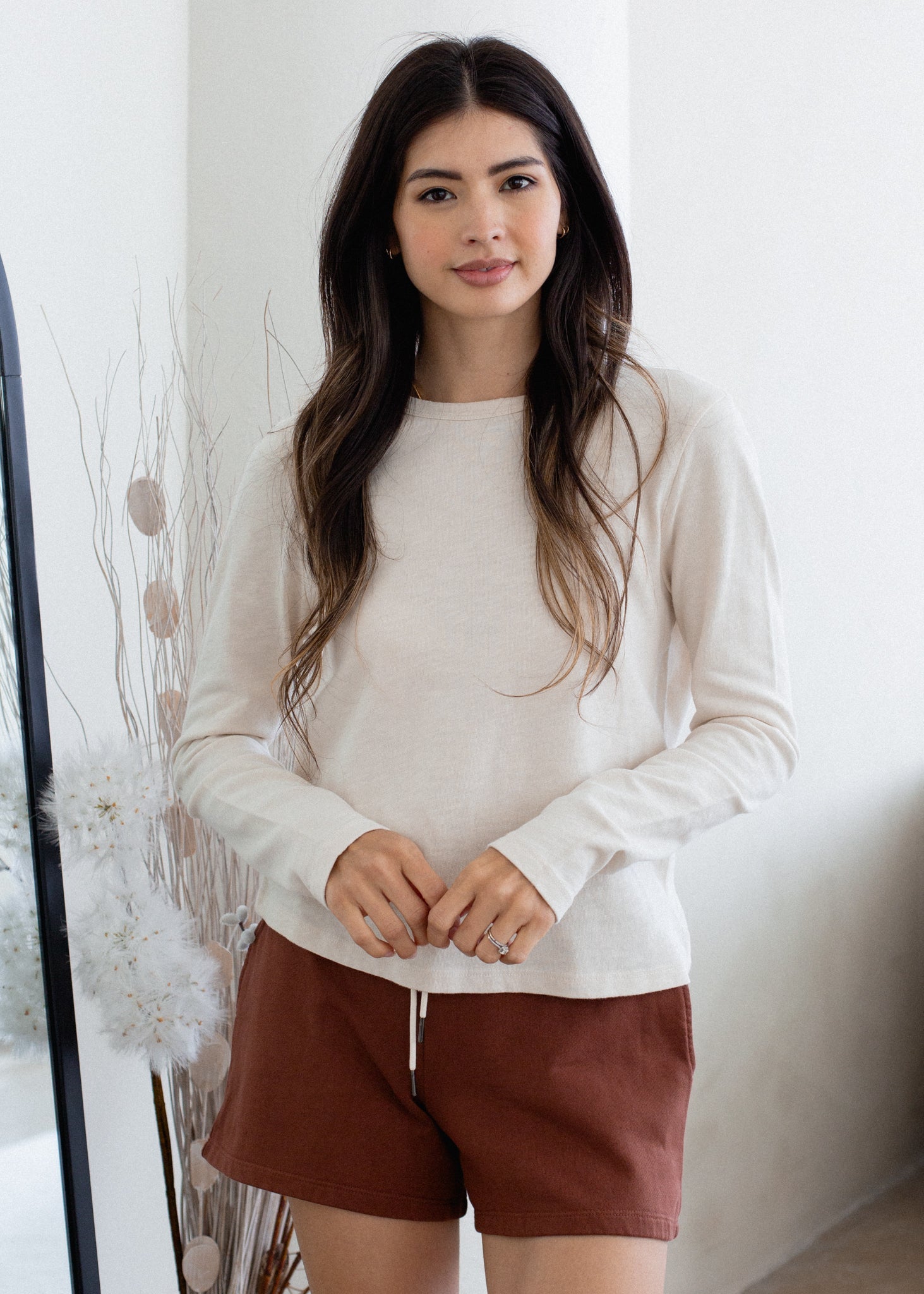 Woman wearing a white sweater and brown shorts indoors