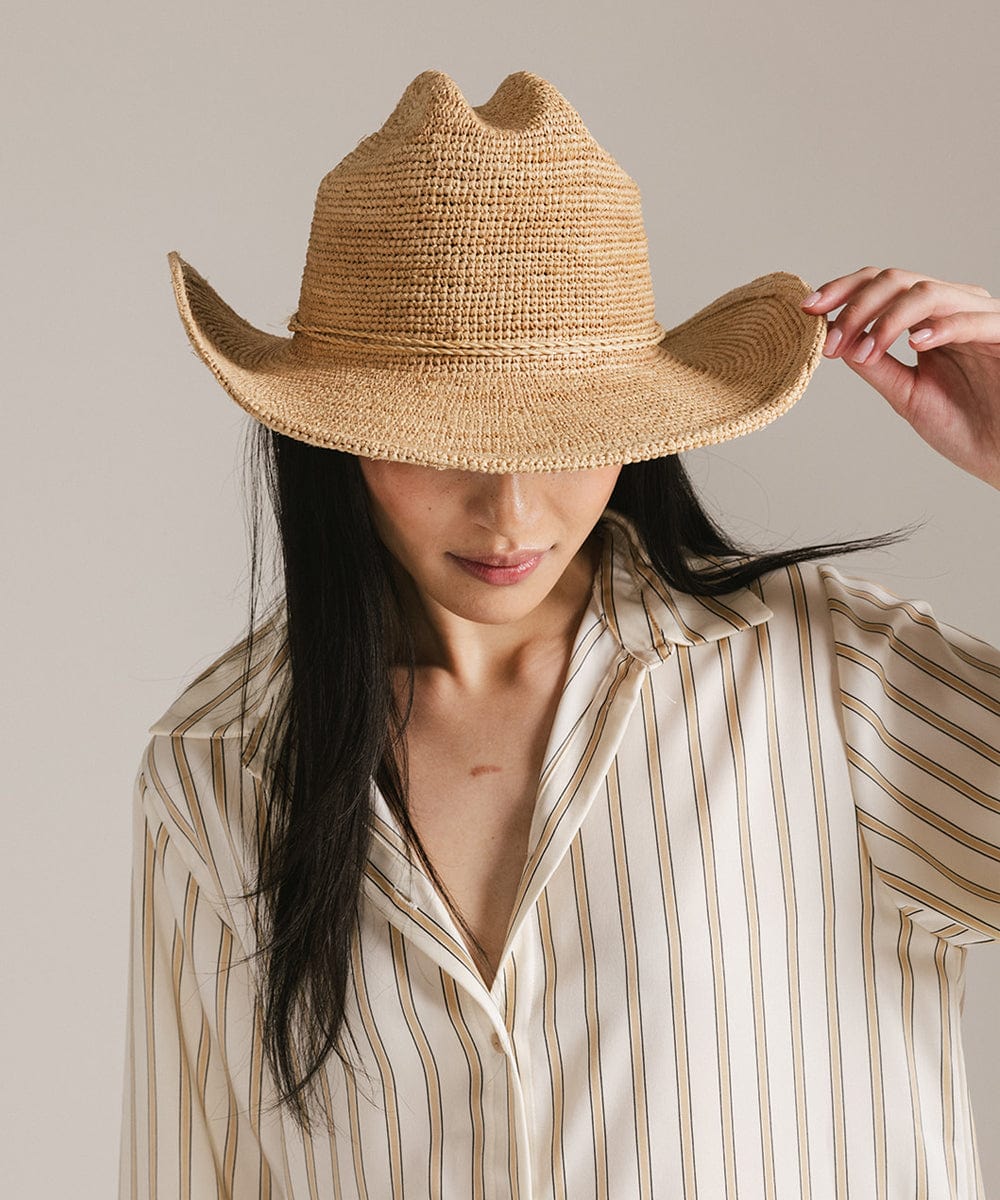 Woman wearing a straw hat and striped shirt against a neutral background