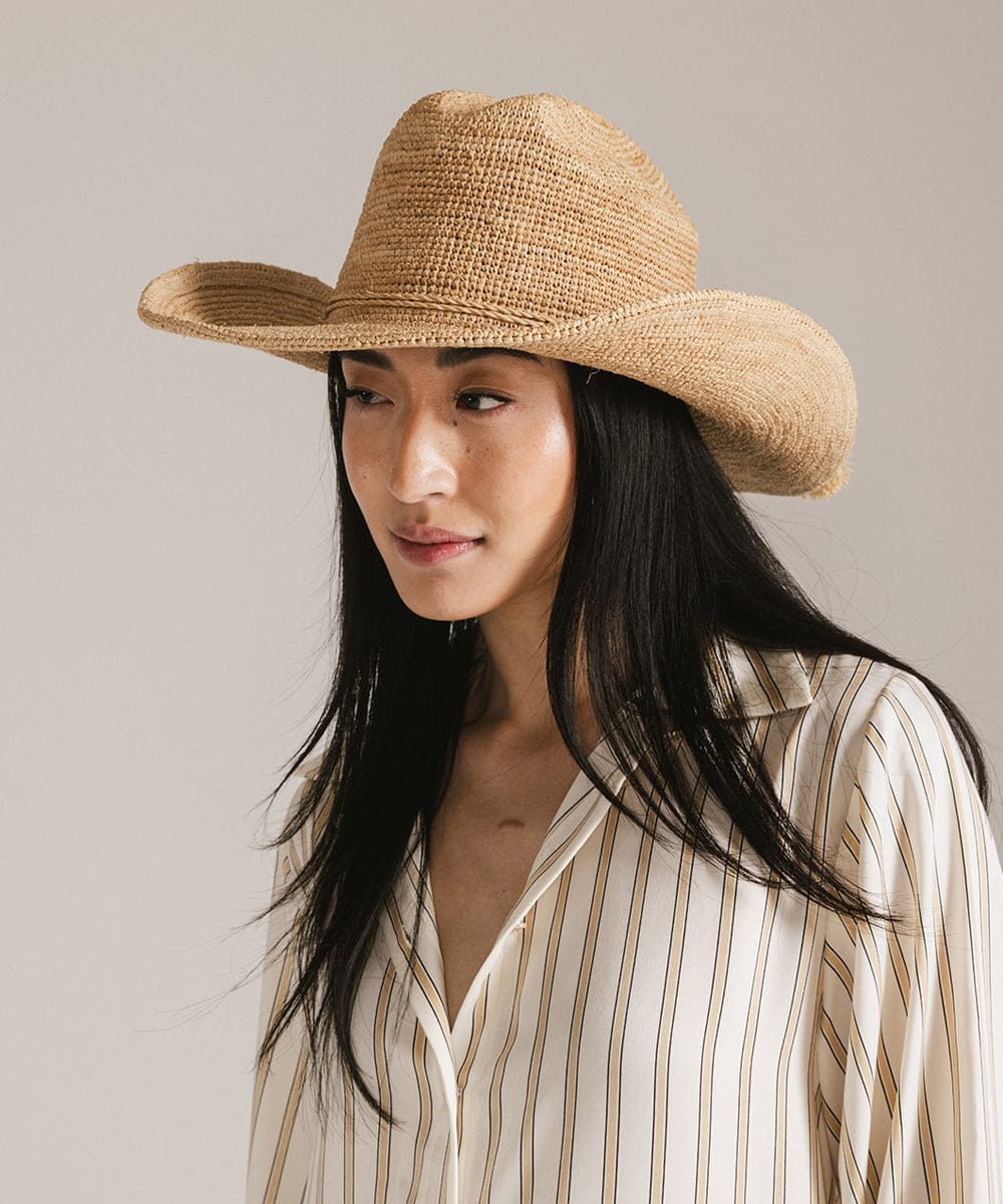 Woman wearing a straw hat with a neutral background