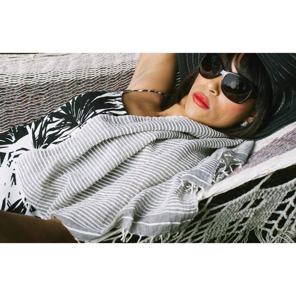 Woman wearing sunglasses and a striped scarf, lying on a patterned surface.