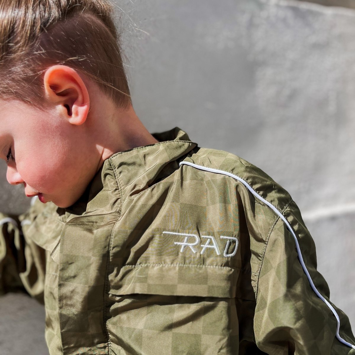 Child wearing a green jacket with 'RAD' embroidery on a neutral background