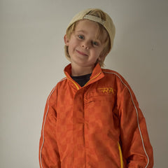 Child wearing an orange jacket with a logo on a plain background