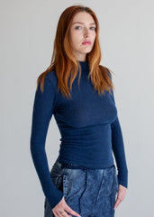 Woman wearing a blue sweater and jeans against a plain background