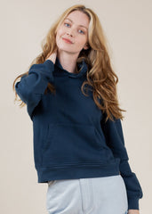 Woman wearing a navy blue hoodie against a beige background