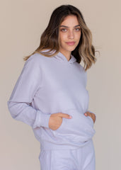 Woman wearing a light purple hoodie and pants against a beige background