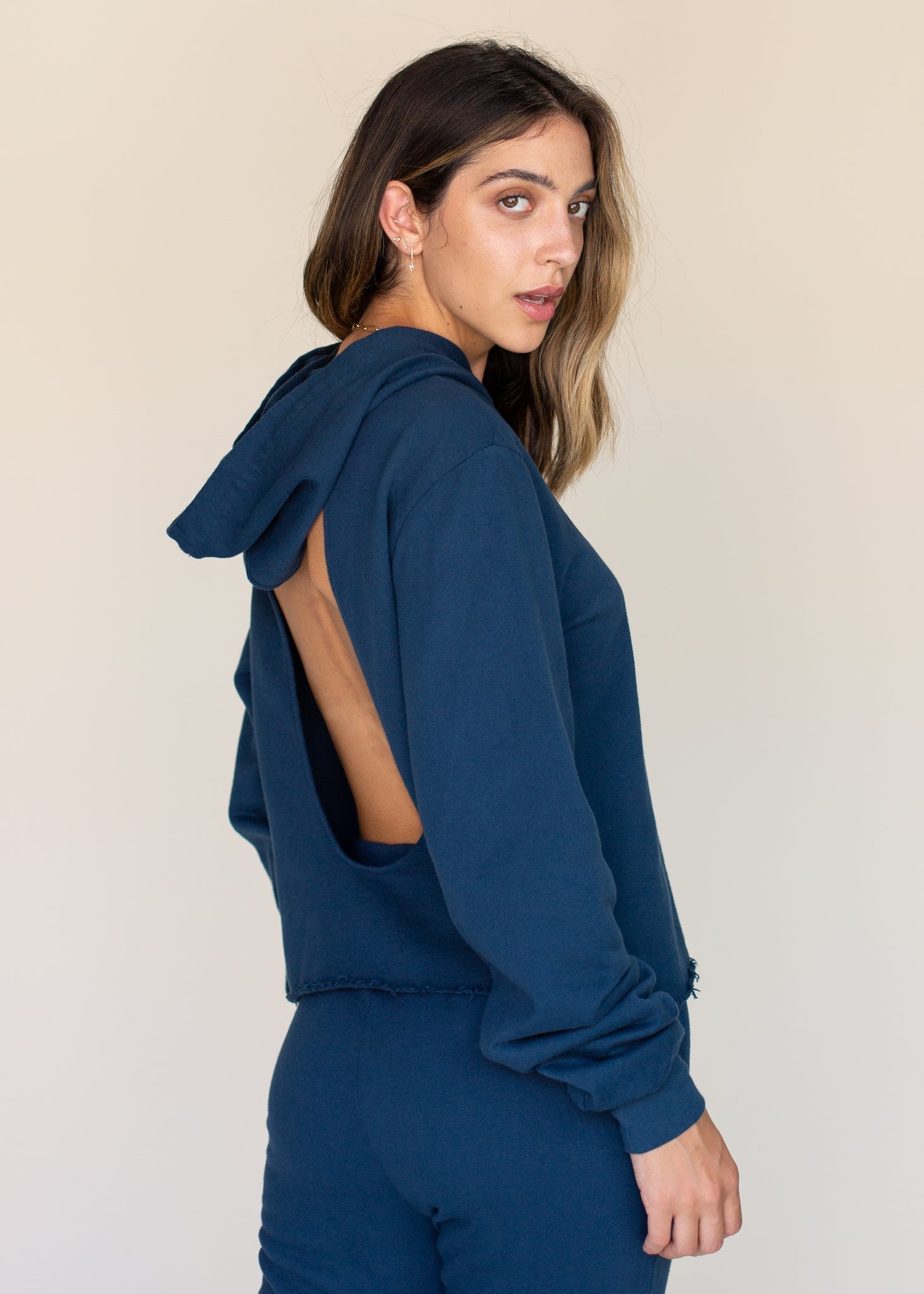 Woman wearing a blue hoodie with cut-out design on a plain background