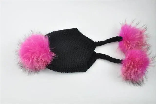 Black knitted cat toy with pink pom-poms on a white background