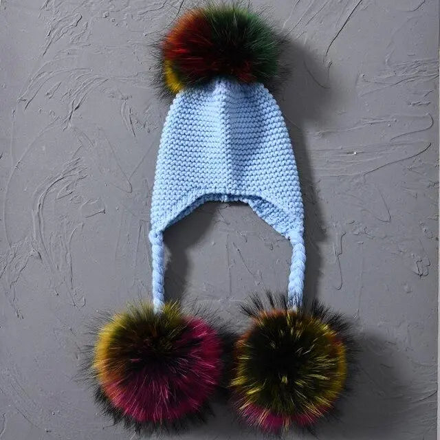 Knitted hat with colorful pom-poms on a textured gray background